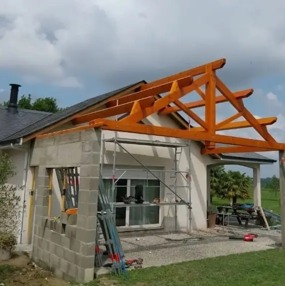 Construction d'une charpente en bois sur une extension de maison en parpaings, avec une ossature traditionnelle et un échafaudage pour les travaux.